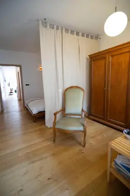 a living room with a chair and a bed at Ka.La Apartment in Bolzano