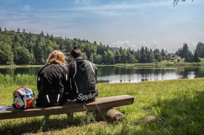 two people sitting on a bench near a lake at Apt. BELLA VISTA nel Cuore della Valle di Cembra. in Segonzano