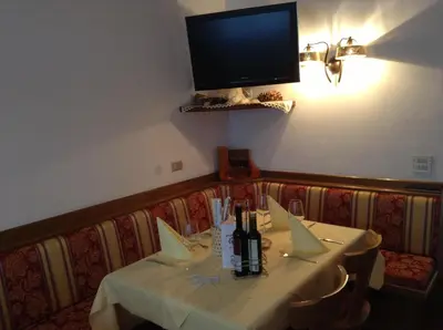 a dining room with a table and a tv on the wall at Hotel Daniela in Merano