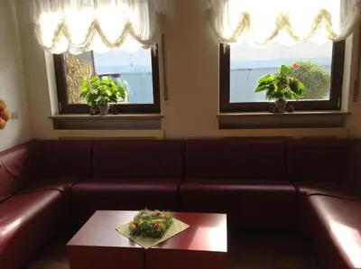 a living room with a couch and two windows at Hotel Daniela in Merano