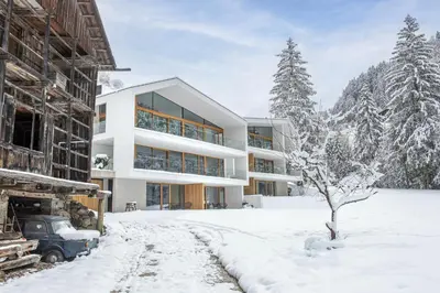 a house in the snow with a tree at Greva Apartments 1 in Santa Cristina in Val Gardena