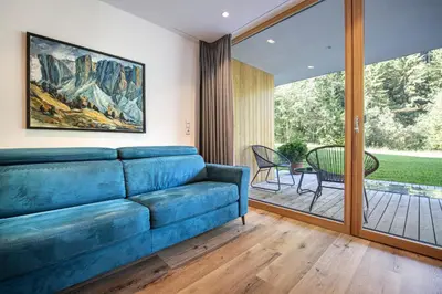 a living room with a blue couch and a patio at Greva Apartments 1 in Santa Cristina in Val Gardena