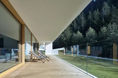 a room with glass walls and chairs on a patio at Greva Apartments 1 in Santa Cristina in Val Gardena