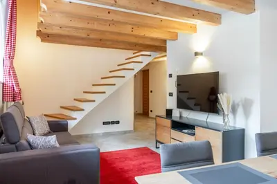 a living room with a staircase and a tv at Apart Dolomites in Castello di Fiemme
