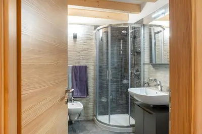 a bathroom with a glass shower and a sink at Apart Dolomites in Castello di Fiemme