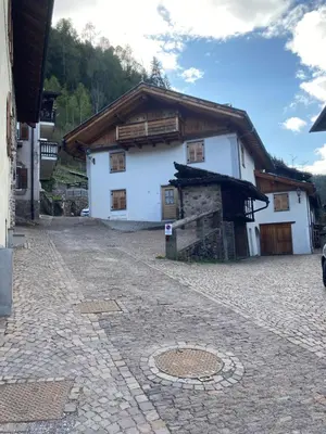 a white building with a wooden roof at Apart Dolomites in Castello di Fiemme
