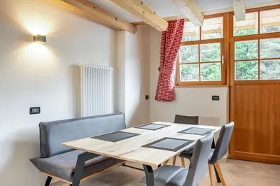 a dining room with a wooden table and chairs at Apart Dolomites in Castello di Fiemme