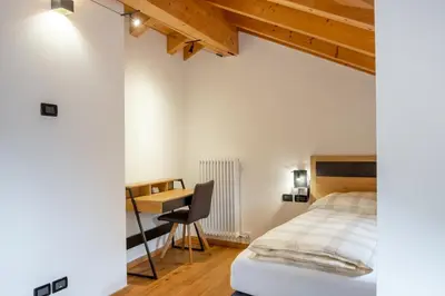 a bedroom with a bed and a desk at Apart Dolomites in Castello di Fiemme