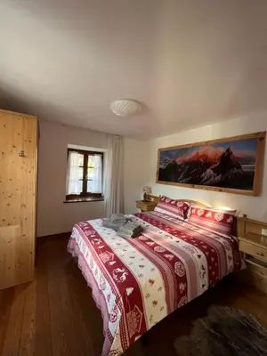 a bedroom with a bed with a red and white blanket at Dolomitihouse ZIRMOL in Fiera di Primiero