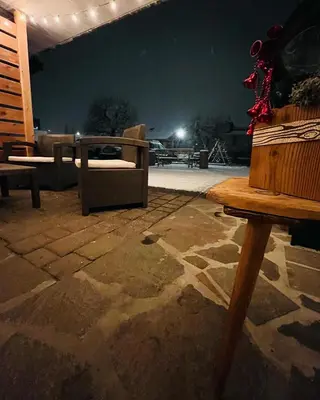 a patio with chairs and a table at night at Dolomitihouse ZIRMOL in Fiera di Primiero