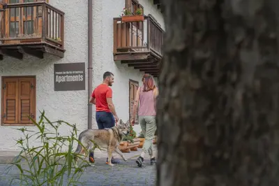 a man and a woman walking a dog down a street at Dolomitihouse ZIRMOL in Fiera di Primiero