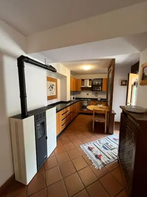 a kitchen with a stove and a table in it at Dolomitihouse ZIRMOL in Fiera di Primiero