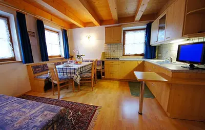 a kitchen with a table and a tv in a room at Apartments Picenin in La Villa