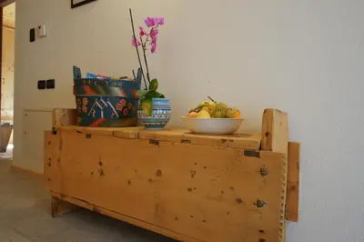 a table with a bowl of fruit and flowers on it at Apartments Picenin in La Villa