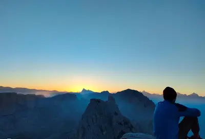 a man sitting on the edge of a mountain watching the sunset at Apartments Picenin in La Villa