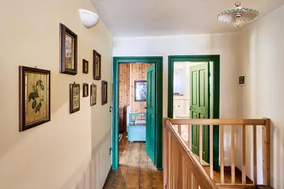 a hallway with green doors and pictures on the walls at Conte Moro, ospitalità in Vanoi in Canale San Bovo