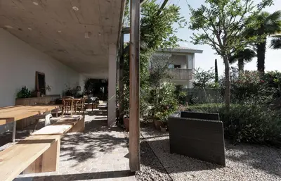 a patio with wooden benches and tables and trees at La Loggia Georg in Pianizza di Sopra