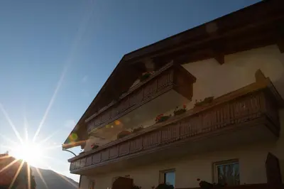 a building with a balcony with the sun in the background at Residence Walchhof in Schenna