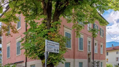 a tree in front of a building with a no parking sign at Appartamento Lichtenegg a Merano in Merano