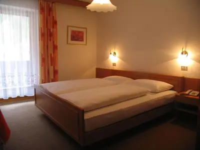 a bedroom with a large bed with white sheets at Hotel Reichegger in Villa Ottone