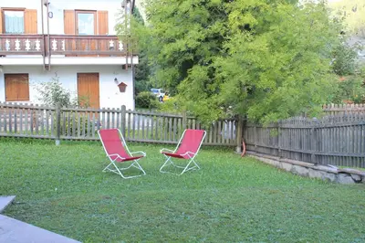 two chairs sitting in the yard in front of a fence at Villetta Enrosadira in Vigo di Fassa