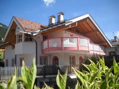 a house with a pink balcony and a fence at Villetta Enrosadira in Vigo di Fassa