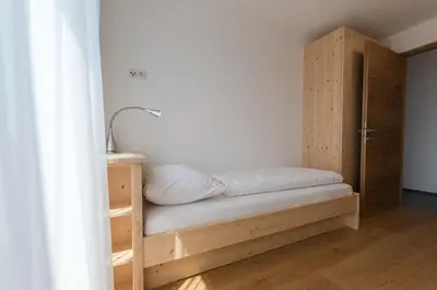 a bed in a room with a wooden cabinet at MESNERHOF CHALET - Ruhe, Rückzug & Südtiroler Charme mit kostenlosem Parken in der Tiefgarage in Bressanone