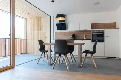 a kitchen with a wooden table and black chairs at MESNERHOF CHALET - Ruhe, Rückzug & Südtiroler Charme mit kostenlosem Parken in der Tiefgarage in Bressanone