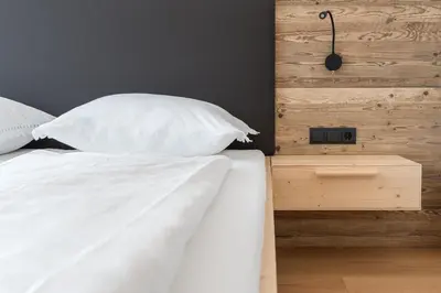 a bed with white sheets and pillows in a bedroom at MESNERHOF CHALET - Ruhe, Rückzug & Südtiroler Charme mit kostenlosem Parken in der Tiefgarage in Bressanone