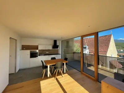 a kitchen and dining room with a table and a balcony at MESNERHOF CHALET - Ruhe, Rückzug & Südtiroler Charme mit kostenlosem Parken in der Tiefgarage in Bressanone
