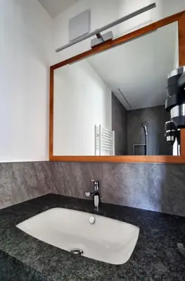 a white sink in a bathroom with a mirror at MESNERHOF CHALET - Ruhe, Rückzug & Südtiroler Charme mit kostenlosem Parken in der Tiefgarage in Bressanone