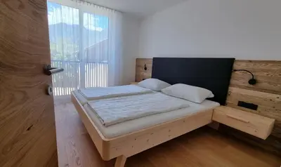 a bed in a room with a large window at MESNERHOF CHALET - Ruhe, Rückzug & Südtiroler Charme mit kostenlosem Parken in der Tiefgarage in Bressanone