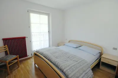 a bedroom with a bed with blue pillows and a window at Casa El Tobià in Pozza di Fassa