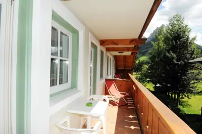 a balcony with a white table and chairs on it at Casa El Tobià in Pozza di Fassa