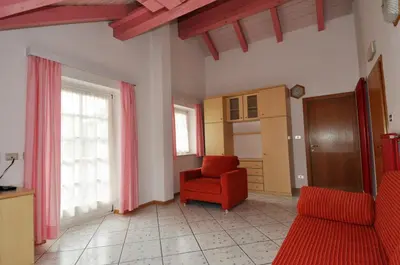 a living room with a red chair and a window at Casa Azzurra in Pozza di Fassa