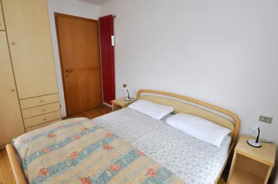 a bedroom with a bed and two tables with lamps at Casa Azzurra in Pozza di Fassa
