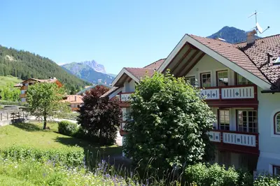 a house in a village with mountains in the background at Casa Azzurra in Pozza di Fassa