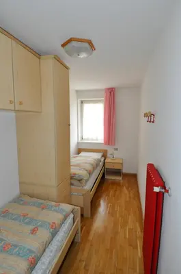 a room with three beds and a window at Casa Azzurra in Pozza di Fassa