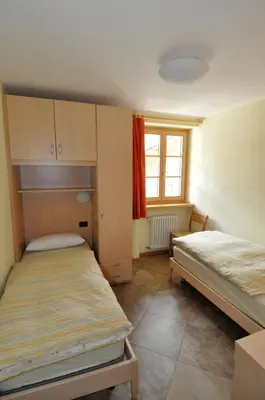 a small room with two beds and a window at La Meisules in Pozza di Fassa
