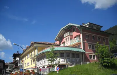 a large building on the side of a street at La Meisules in Pozza di Fassa