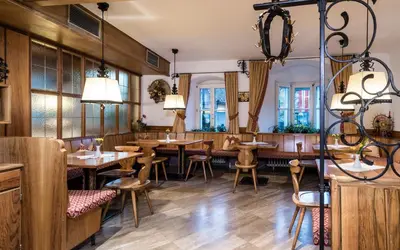 a restaurant with wooden tables and chairs and windows at Hotel Grüner Baum in Bressanone