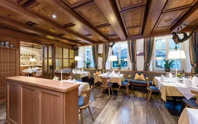 a restaurant with white tables and chairs and windows at Hotel Grüner Baum in Bressanone