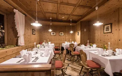 a dining room with white tables and chairs and lights at Hotel Grüner Baum in Bressanone