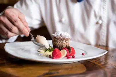 a person eating a dessert with strawberries on a plate at Hotel Grüner Baum in Bressanone
