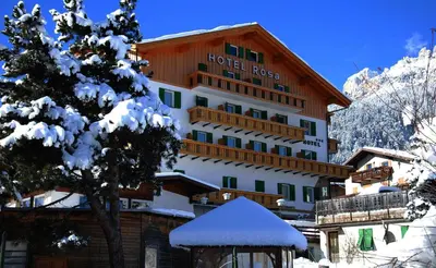 a dining room with tables and chairs and wooden ceilings at Hotel Rosa Wellness & SPA in Vigo di Fassa