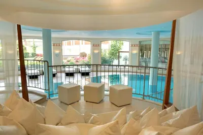 a room with a pool and two white chairs at Hotel Ansitz Plantiz in Merano