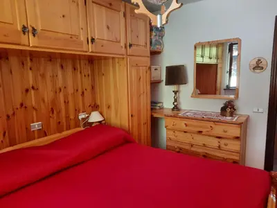 a bedroom with a red bed and a dresser at Finestra sul Cermis in Carano