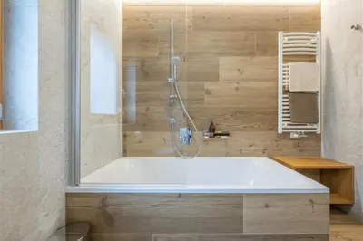 a bathroom with a tub and a shower at Ciasa Nene Franzl in Badia