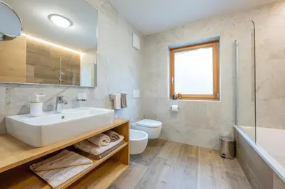 a bathroom with a sink and a tub and a toilet at Ciasa Nene Franzl in Badia