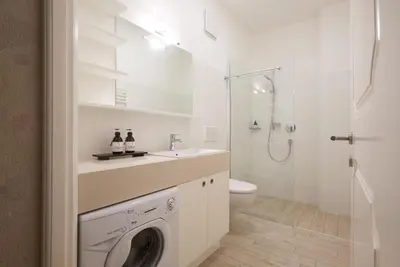 a white bathroom with a washing machine in it at Argentieri Apartment in Bolzano